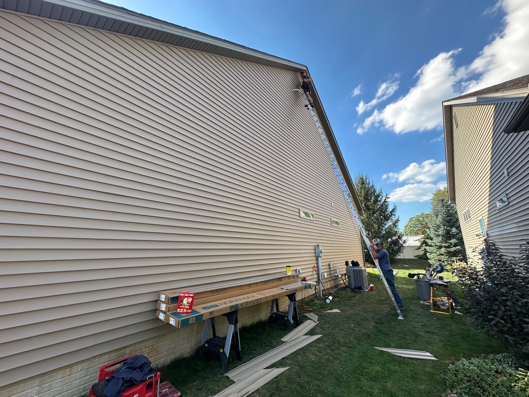 Vinyl siding installation in progress on a tall gable wall